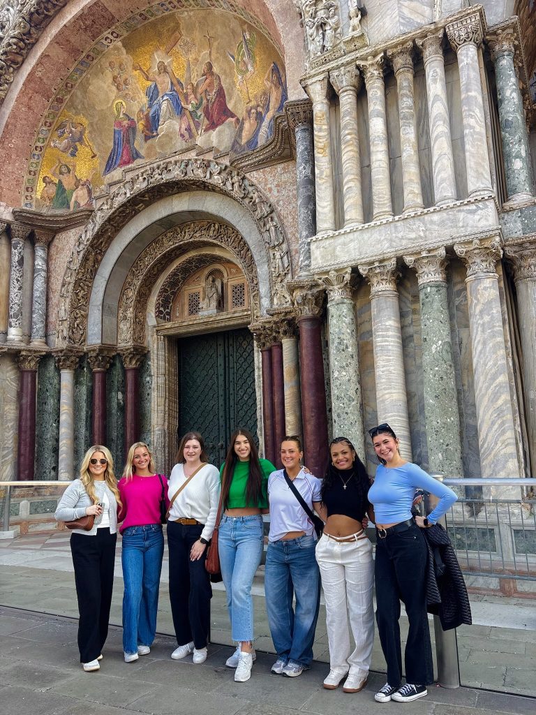Group of girls smiling in front of St. Mark's Basilica on a guided trip in Venice Italy