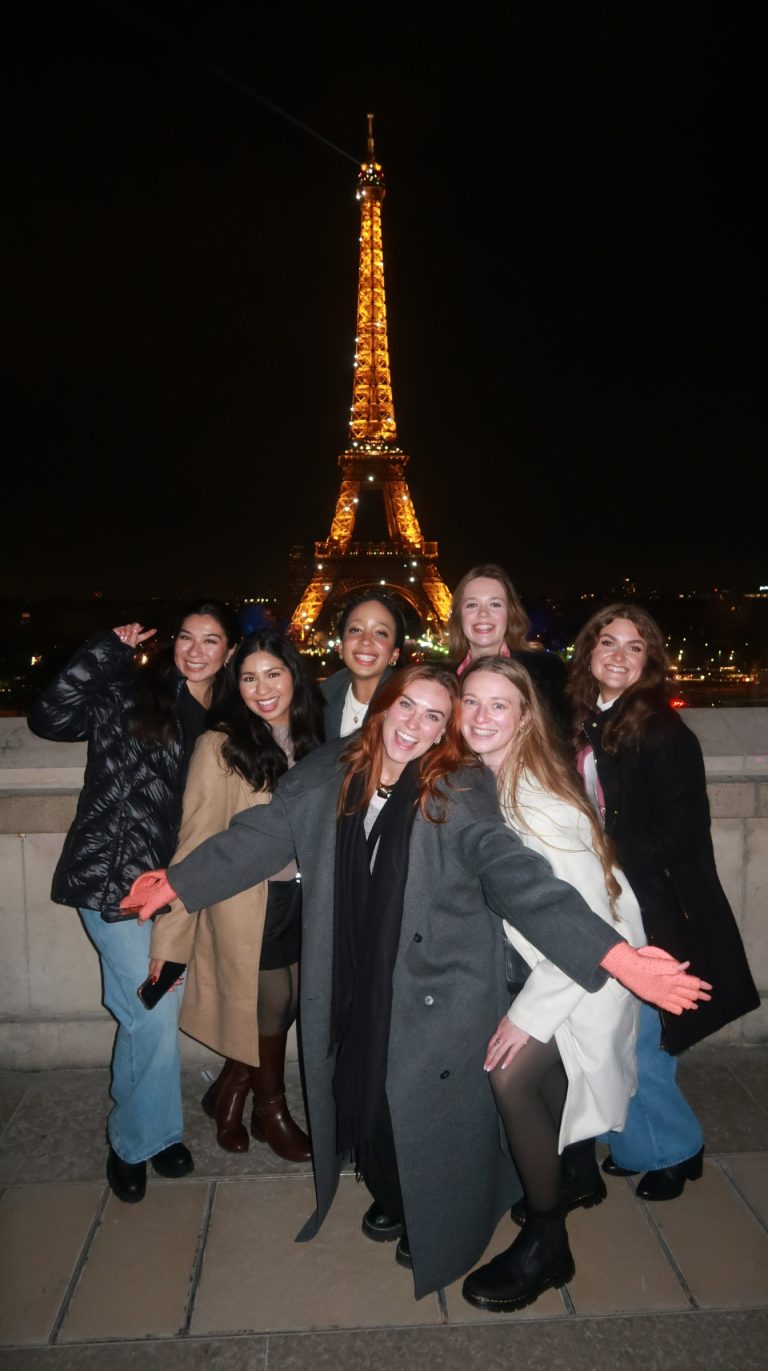 Group of women smiling in front of the Eiffel Tower in Paris on a guided tour
