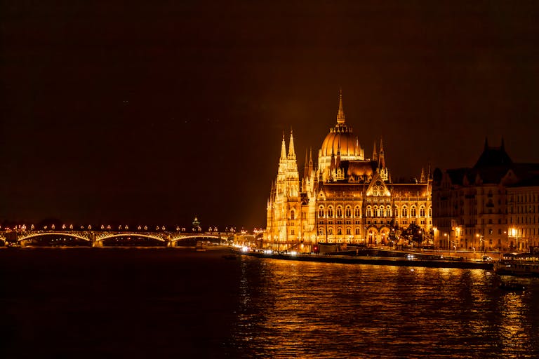 Stunning view of the illuminated Budapest Parliament and bridge reflecting on the Danube River at night.