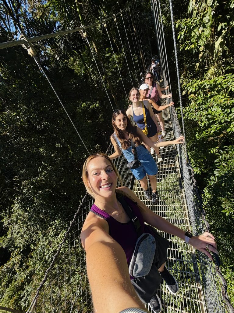 A group of women pose for a selfie on a rope bridge in the Costa Rican rainforest