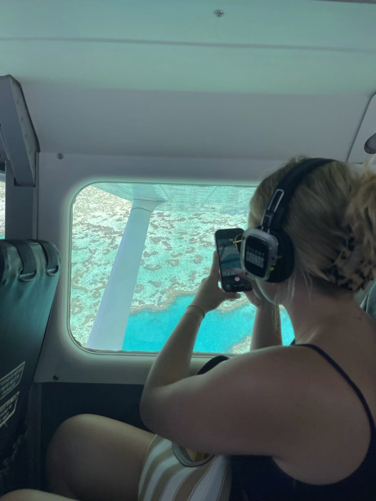 A female passenger on a scenic flight over the Great Barrier Reef takes a photo out the plane window
