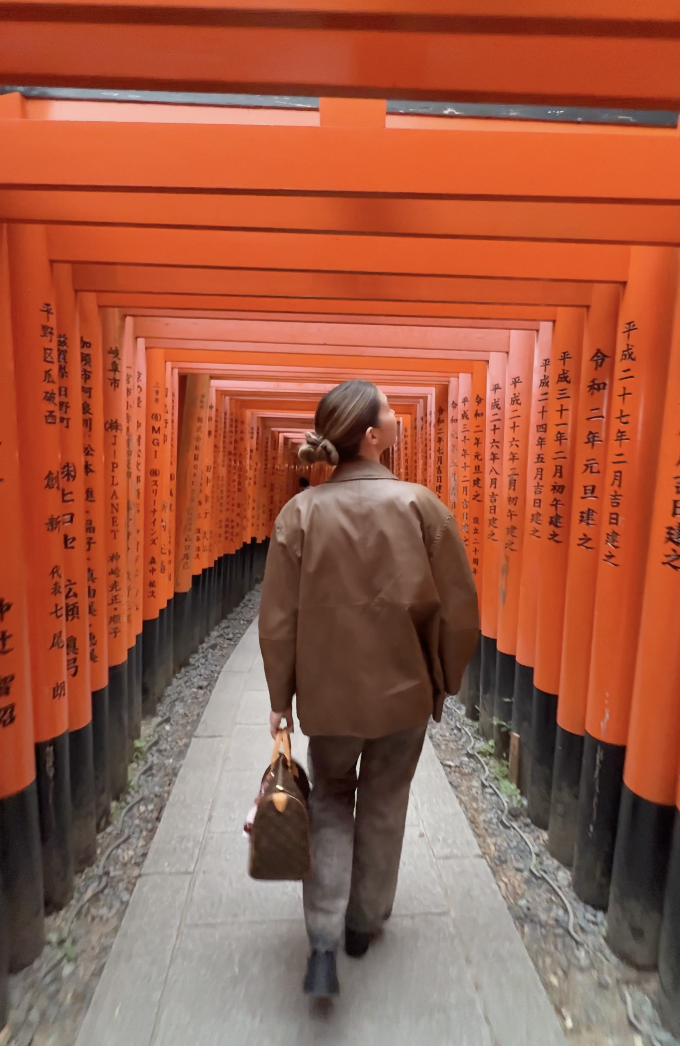 girl walks under the red arches of Fushimi Inari in Kyoto Japan