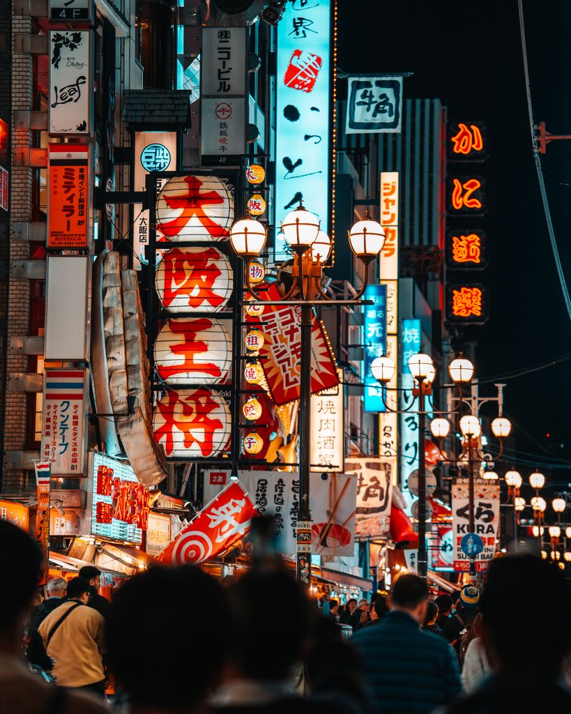 Explore the vibrant nightlife of Osaka's Dotonbori district with bustling crowds and bright neon signs.
